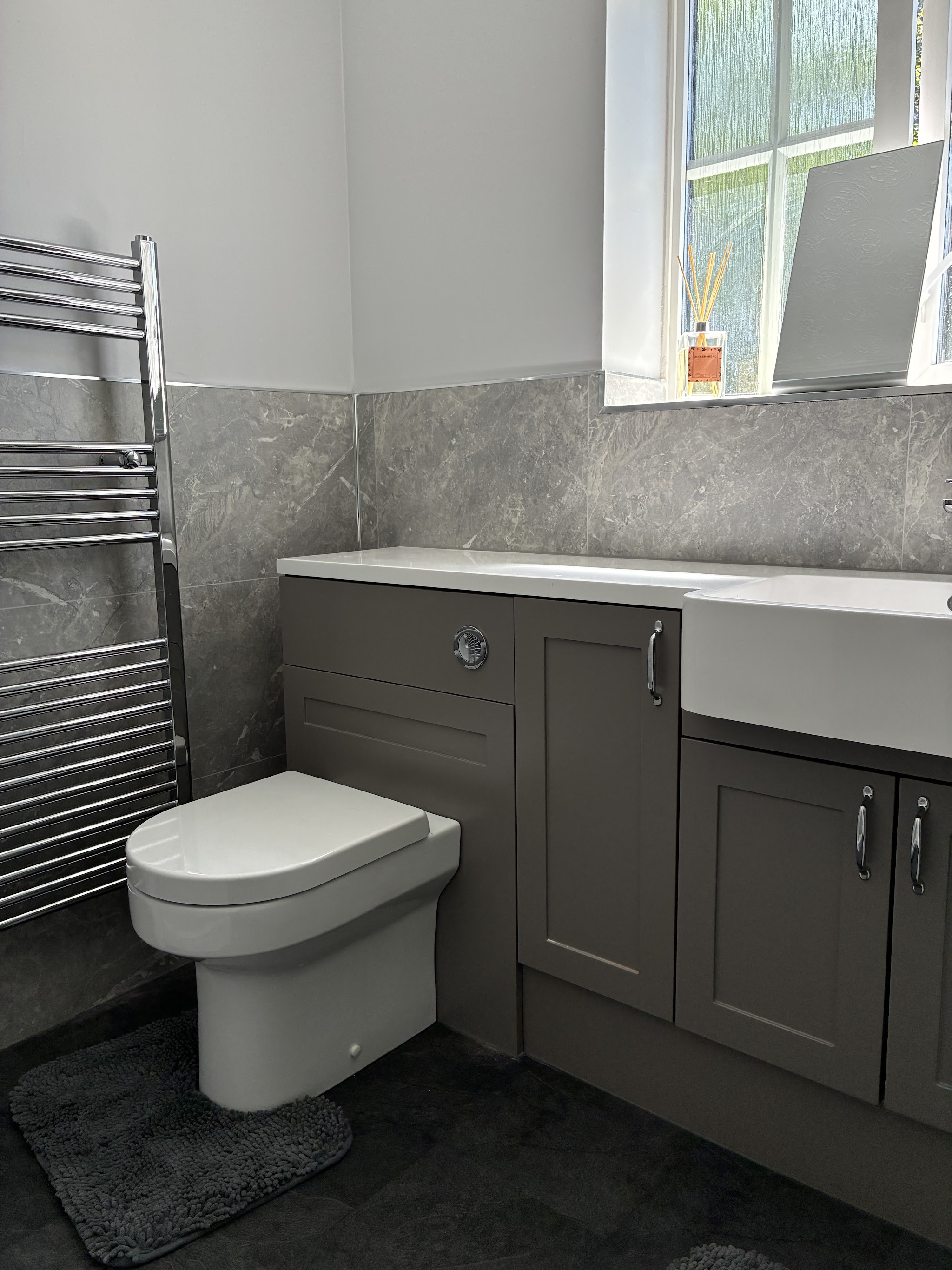 Grey shaker fitted bathroom furniture with a back-to-wall toilet and chrome towel radiator